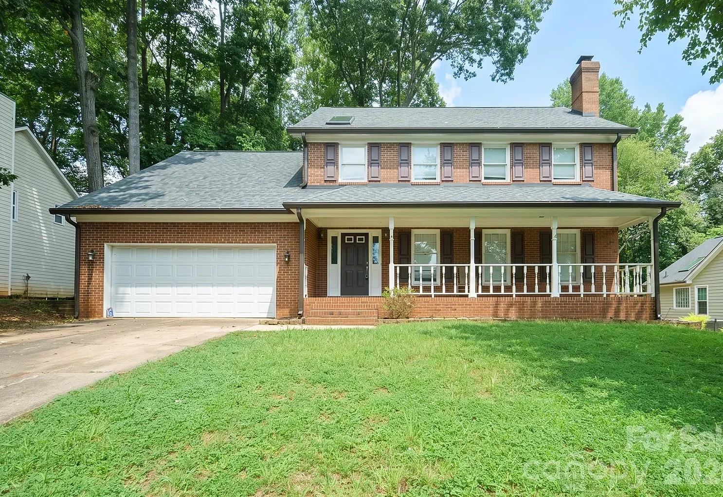 The home before: red brick with a white garage door, white porch railings and dark red shutters