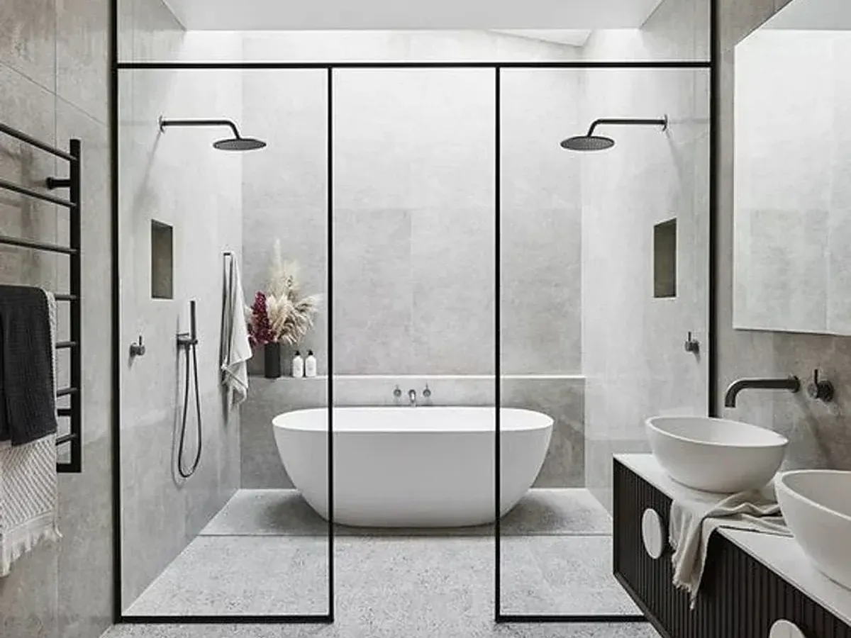 A bathroom with two rain showers behind glass and a tub