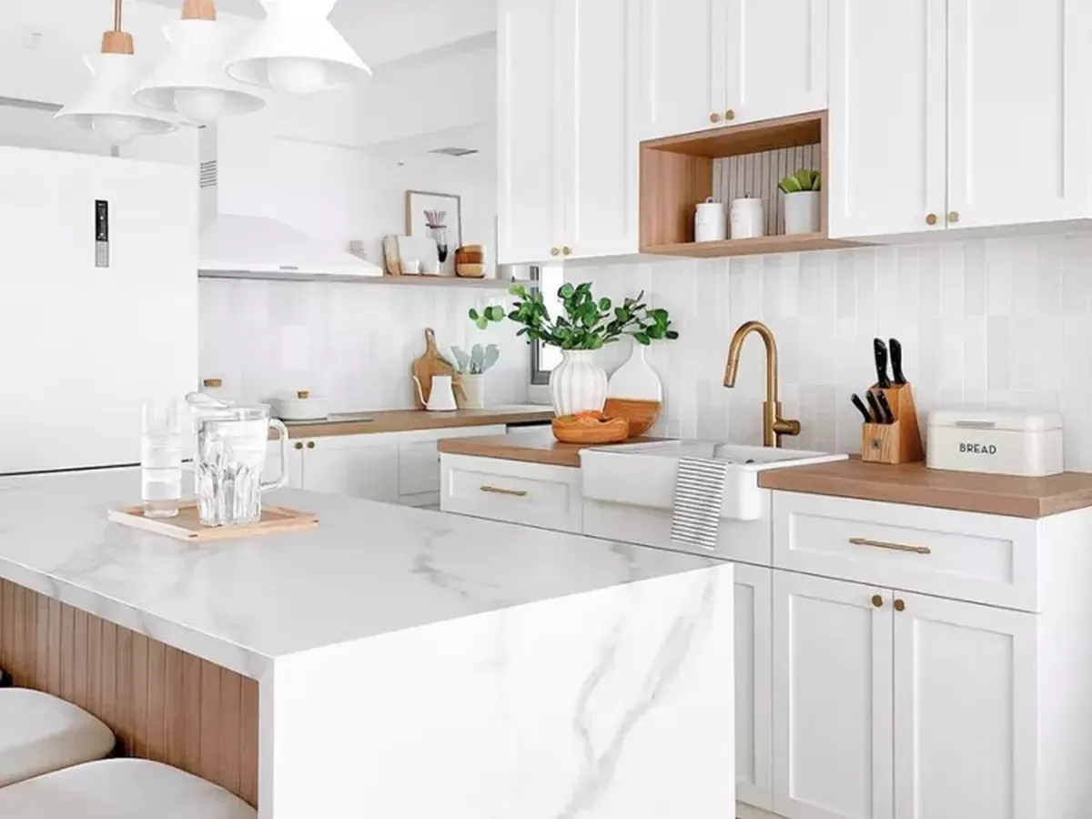 A bright white kitchen with a marble waterfall island